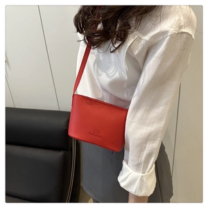 Detail of red bucket bag showing pebbled leather texture and embossed logo branding