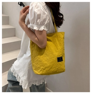 Detail of yellow minimalist tote bag with F logo patch and long shoulder strap
