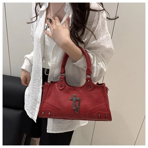 Detail of red punk shoulder bag with metal cross pendant and silver studs on model