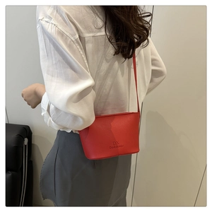 Detail of red leather bucket bag with DX logo and textured lychee pattern finish