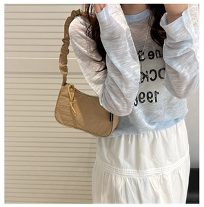 Detail of khaki nylon shoulder bag featuring textured ruched strap and side label