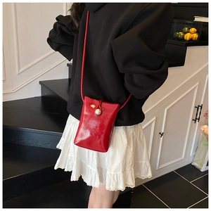 Detail of red patent leather mini crossbody bag with elegant pearl clasp on a model