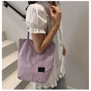 Detailed view of lavender nylon tote bag with black designer label and square texture