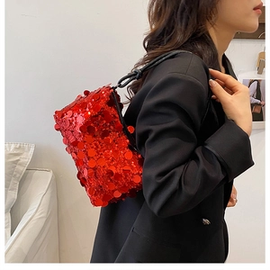 Close-up of vibrant red sequined shoulder bag styled with a professional black blazer