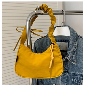 Detail of yellow nylon shoulder bag with pleated cloud pleated strap and ribbon bow decoration