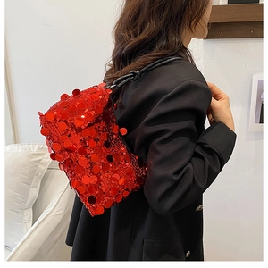 Close-up of red sequin shoulder bag showing reflective texture on black blazer