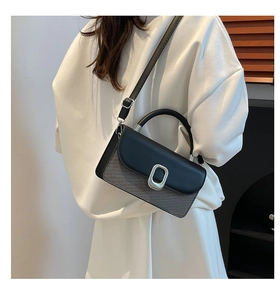 Detail of a modern crossbody bag featuring grey textured fabric and silver metal buckle