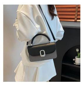 Detail of a black and grey contrast crossbody bag with a large silver circular ring buckle