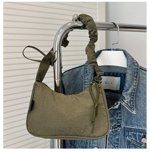 Detail of olive green nylon shoulder bag featuring a unique ruched handle and drawstring