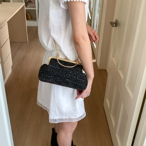 Fashionable black woven shoulder bag with gold chain strap shown on model for women