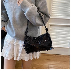 Fashionable black sequin shoulder bag shown on model with shiny round disc detailing