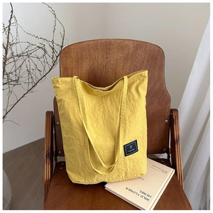 Detail view of yellow canvas bucket bag with texture on a brown wooden chair