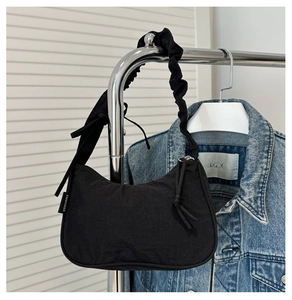 Detail of black nylon crescent shoulder bag with pleated strap on a hanger