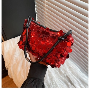 Macro detail of red sequin shoulder bag showing glossy texture and black knotted strap