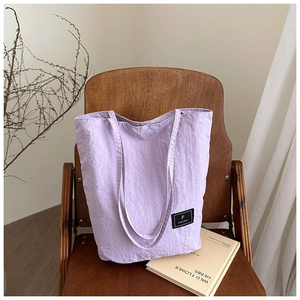 Detail of light purple canvas tote bag on wooden chair with minimalist brand tag