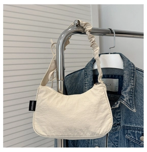 Detail of beige hobo bag with unique scrunchie shoulder strap and side brand label