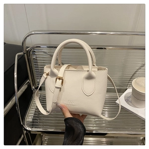 Detailed close-up of a white lychee leather texture crossbody bag with gold hardware