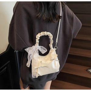 Detail of crossbody bag with ruffled cloud handle and decorative lace ribbon