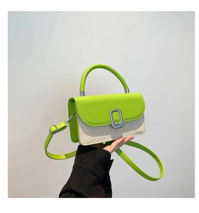 Detail of neon green leather flap and cream canvas body with silver oval metal buckle
