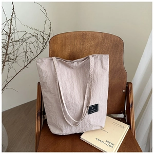 Detail view of pink nylon bucket bag with natural wrinkles and brand label on wooden chair