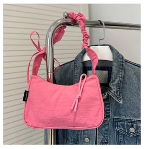 Detail of a bright pink nylon shoulder bag with a decorative side bow and knot zipper