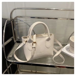 Detailed view of white litchi textured mini tote bag with dual handles and long strap
