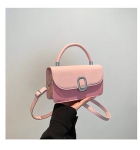 Pink shoulder bag detail showing woven texture, smooth leather lid, and metal clasp