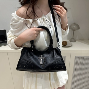 Gothic black PU leather shoulder bag with punk studs and cross charm in a home setting