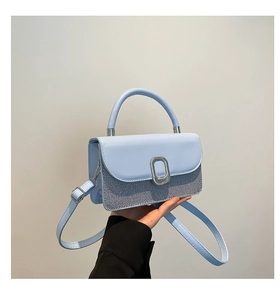 Close-up of light blue small square bag with textured fabric and metal buckle detail