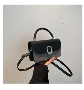 Detail of the chic black leather and grey denim patchwork bag with silver metal buckle