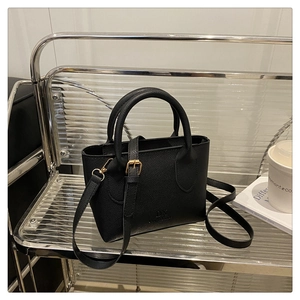 Detailed close-up of black lychee grain leather handbag with gold-tone DX logo hardware