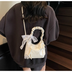 Detail of cream balletcore crossbody bag featuring a large lace bow and scrunchie handle