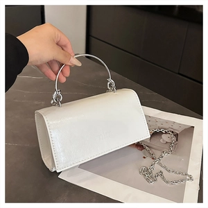 Detailaufnahme der weißen Lederhandtasche mit silbernem Rundgriff und Kettenriemen