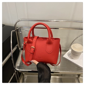 Close-up of a red litchi texture crossbody bag with adjustable strap and top handle