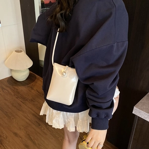 Minimalist cream shoulder bag with large pearl button closure and thin strap