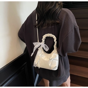 Détail du sac nuage blanc avec nœud décoratif et écharpe en dentelle sur la poignée