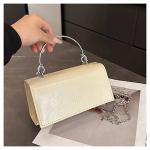 Detail der cremeweißen PU-Lederhandtasche mit mim-Logo und Metallkettenriemen