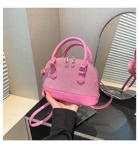 Close-up of pink woven shell bag featuring gold hardware and elegant top handles