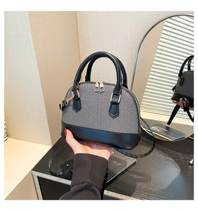 Detail of shell-shaped crossbody bag featuring textured fabric and matte leather base
