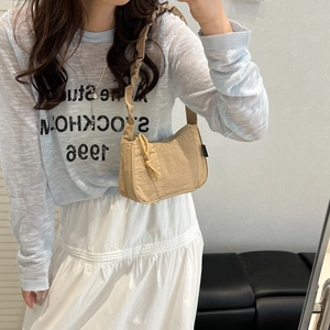 Light khaki nylon shoulder bag with ruffled strap and rounded silhouette on model