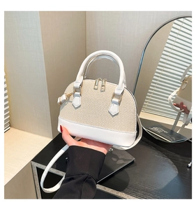 Detail of a beige woven shell bag with white leather trim and golden zippers