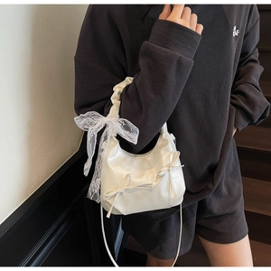 Detail of white hobo bag with lace bow decoration and faux leather glossy finish