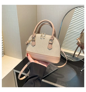 Close-up of beige woven texture shell bag with cream PU leather handles and gold zippers