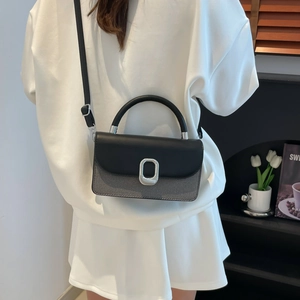Chic two-tone crossbody bag with silver buckle worn by a model in a lifestyle setting