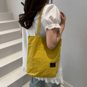 Minimalist ginger yellow nylon tote bag for women showing a casual commuter shoulder style