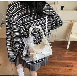 Chic cream white hobo bag with delicate bow accents and lace trim shown as crossbody