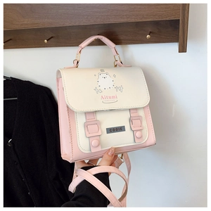 Close-up of pink and cream cat-patterned backpack with stylish metal hardware and top handle