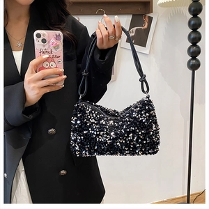 Detail of a chic black sequin shoulder bag with decorative knotted strap shown in use
