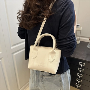 Chic beige lychee leather mini crossbody bag for women worn by a model in a stylish setting