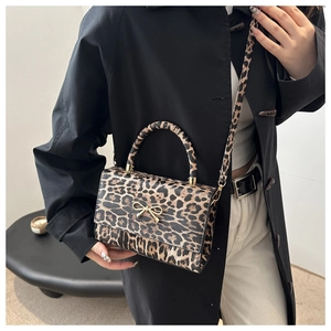 Detail of leopard print handbag featuring a gold bow accent and crossbody strap